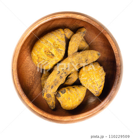 Dried whole turmeric root in a wooden bowl. Dehydrated rhizomes of Curcuma longa, also called tumeric. Used as spice for curries, as coloring and flavoring agent, and as haridra in Ayurvedic medicine. Dried whole turmeric root in a wooden bowl. Dehydrated rhizomes of Curcuma longa, also called tumeric. Used as spice for curries, as coloring and flavoring agent, and as haridra in Ayurvedic medicine. 110229509