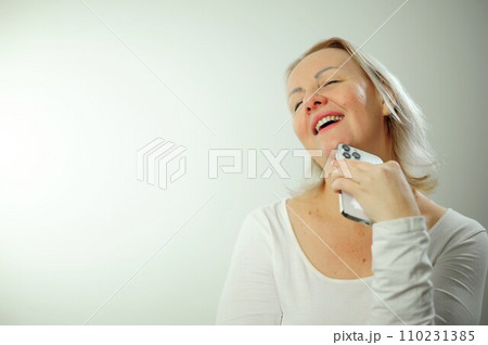 adult woman in bliss holds the phone and she is just happy she threw her head back opened her mouth she shows white teeth has blond hair her eyes are closed she dreams place for advertising and text adult woman in bliss holds the phone and she is just happy she threw her head back opened her mouth she shows white teeth has blond hair her eyes are closed she dreams place for advertising and text 110231385