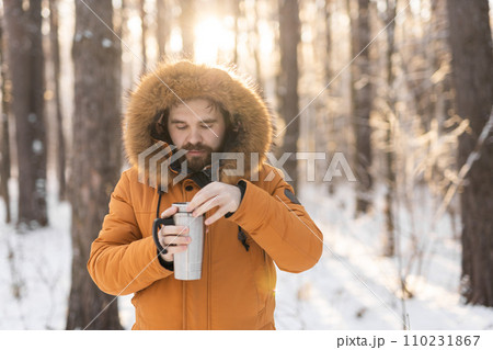 Close-up portrait handsome bearded millennial man in winter clothes and with thermos snow outdoor. Cold season and hot beverage in winter time, Copy space Close-up portrait handsome bearded millennial man in winter clothes and with thermos snow outdoor. Cold season and hot beverage in winter time, Copy space 110231867