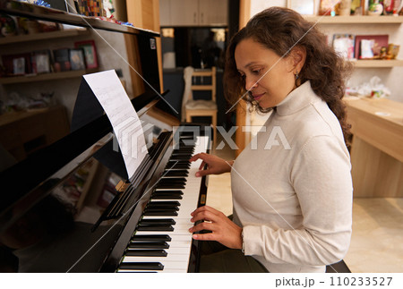Confident woman playing grand piano at home. People. Music. Hobbies and leisure Confident woman playing grand piano at home. People. Music. Hobbies and leisure 110233527