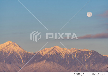 【月素材】冬の朝焼けした北アルプスと満月【長野県】 110234857