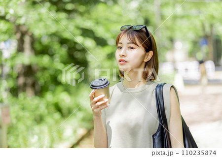 新緑の中コーヒーを飲む若い女性 110235874
