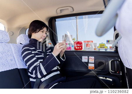 タクシーの後部座席でスマホを使う若い女性 タクシーの後部座席でスマホを使う若い女性 110236082