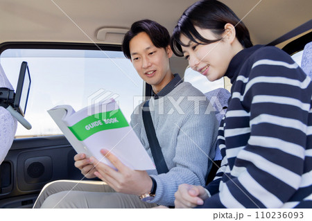 旅行先のタクシーの後部座席でガイドブックを吟味するカップル 110236093