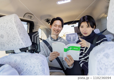 旅行先のタクシーの後部座席でガイドブックを吟味するカップル 旅行先のタクシーの後部座席でガイドブックを吟味するカップル 110236094