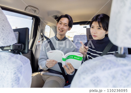 旅行先のタクシーの後部座席でガイドブックを吟味するカップル 110236095