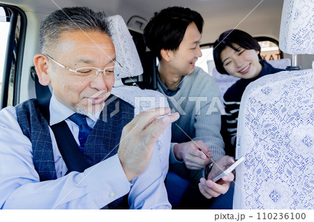 旅行先のタクシー内でスマホを見せて行き先を伝えるカップル 旅行先のタクシー内でスマホを見せて行き先を伝えるカップル 110236100