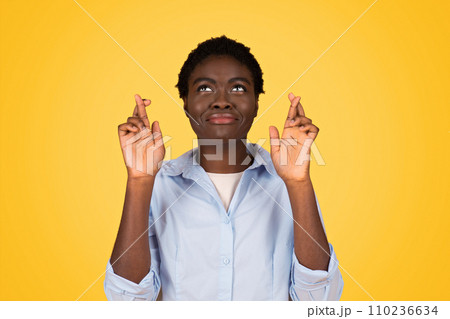 A hopeful black woman student with crossed fingers, embodying optimism and aspiration A hopeful black woman student with crossed fingers, embodying optimism and aspiration 110236634