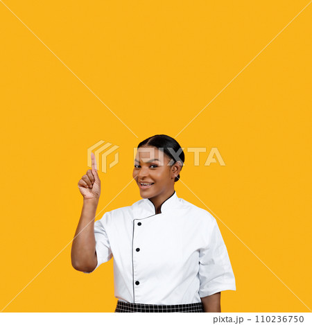 Joyful black female chef with bright smile pointing upwards, suggesting successful idea Joyful black female chef with bright smile pointing upwards, suggesting successful idea 110236750