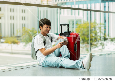 Asian guy tourist using smartphone, waiting for flight Asian guy tourist using smartphone, waiting for flight 110237676