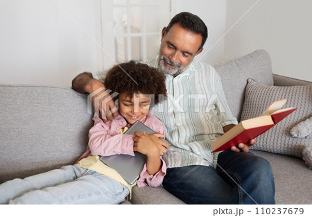 grandfather and grandchild spending time with tablet and book indoors 110237679