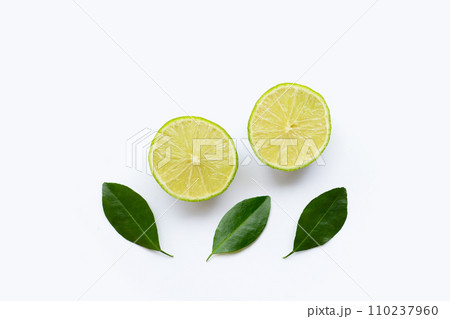 Ripe limes with green leaves on white. 110237960