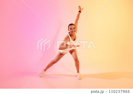 A joyful woman with a shaved head in a dynamic yoga pose, wearing a white sports outfit and sneakers A joyful woman with a shaved head in a dynamic yoga pose, wearing a white sports outfit and sneakers 110237988
