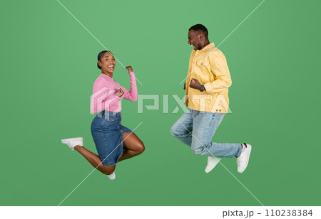 Emotional young african american couple jumping up and clenching fists Emotional young african american couple jumping up and clenching fists 110238384
