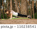 Strong little female sportsman standing on plank on green mat in nature. Focused athletic girl training outdoor. 110238541
