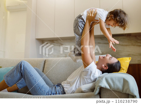 Mother and child playing airplane game on sofa, having fun at home 110238790