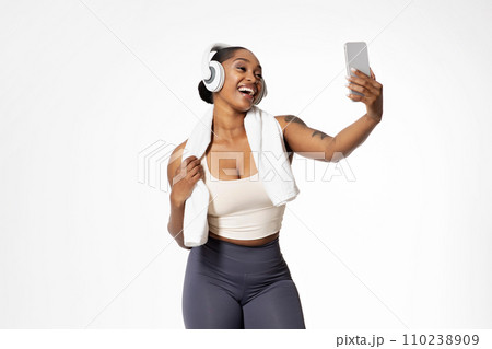 african lady in sportswear and headphones making video call, studio 110238909