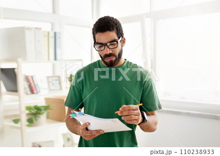 Concentrated man with glasses and a beard, wearing a green t-shirt Concentrated man with glasses and a beard, wearing a green t-shirt 110238933