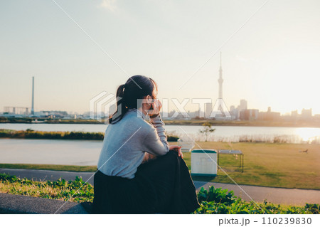 夕暮れに佇む女子大生 110239830