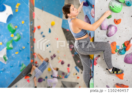 Young woman exercising on wall in climbing gym during bouldering training Young woman exercising on wall in climbing gym during bouldering training 110240457