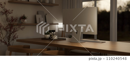 A modern, cosy office workspace in the evening with a computer on a wooden table. A modern, cosy office workspace in the evening with a computer on a wooden table. 110240548