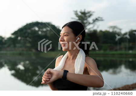 Sport young woman looking at smartwatch on her wrist, tracking fitness activity during training outdoors 110240660