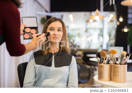 Hands of makeup artist applying powder brush on female client face 110240661