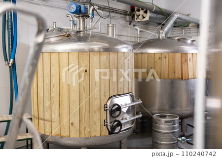 Interior of small brewery with tanks for beer fermentation and kegs 110240742