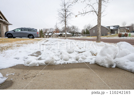 Residential sidewalk with section that has been cleared of snow next to a covered path. Residential sidewalk with section that has been cleared of snow next to a covered path. 110242165