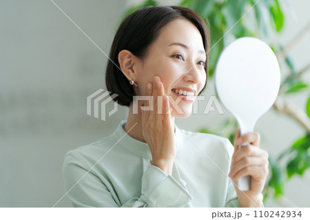 鏡を持ち肌のチェックをする女性 110242934