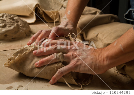 Artisan Working Wet Clay Wrapped in Beige Canvas on Crafting Table 110244293
