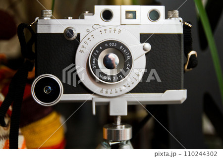 Vintage Camera on Tripod in Softly Lit Studio Setting Vintage Camera on Tripod in Softly Lit Studio Setting 110244302