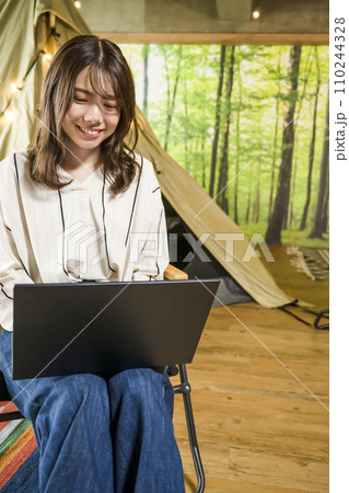 ワーケーション　キャンプ場で仕事をする若い女性 110244328