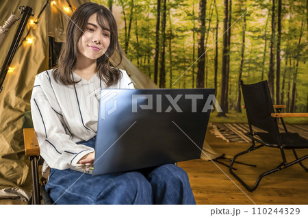 ワーケーション　キャンプ場で仕事をする若い女性 110244329
