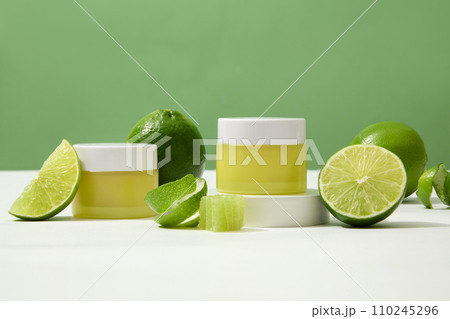 Pair of unbranded yellow cosmetic jars showcased on a white surface with fresh lemons. Blank labels offer space for custom lettering design, perfect for branding. 110245296