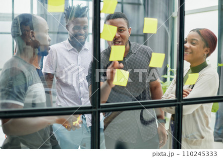 a team of young designers sticking notes on glass in a modern office 110245333