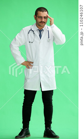 male doctor in a white coat on a green background shows a headache male doctor in a white coat on a green background shows a headache 110246107