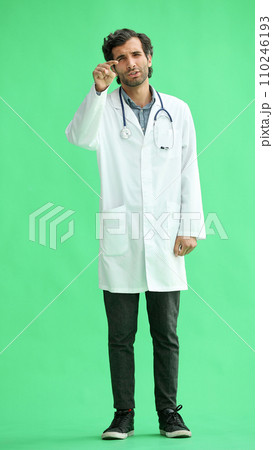 male doctor in a white coat on a green background thinks male doctor in a white coat on a green background thinks 110246193