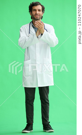 male doctor in a white coat on a green background applauds 110247070