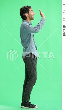 young man in full growth. isolated on green background shows hello with hand 110247281