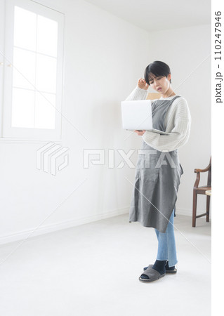 部屋でパソコンを使い、売上などを困る・悩む表情のショップの販売員や接客業のような女性 110247946