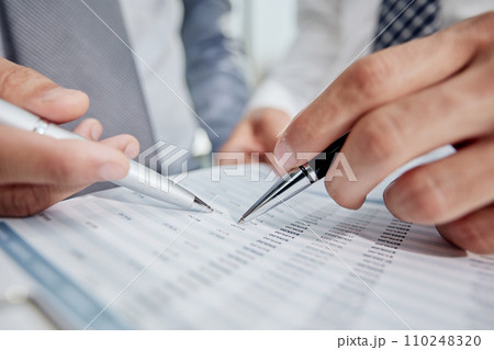 An office worker in a white shirt looks at the financial report. Close-up 110248320