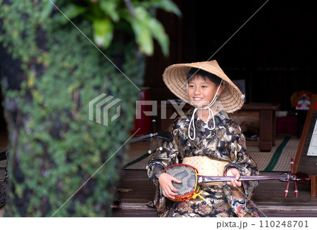沖縄の民族衣装を着て三線を引く男の子 110248701