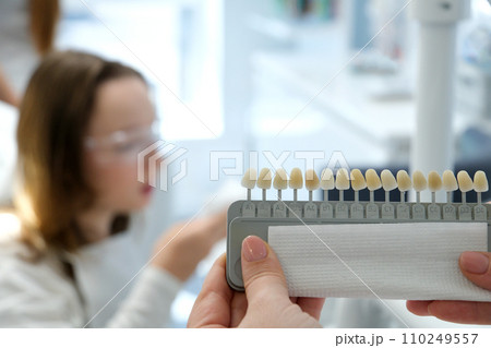 video tooth whitening, perfect white crown teeth close up with shade guide bleach color, female veneer smile, dental care and stomatology, dentistry, copyspace. 110249557