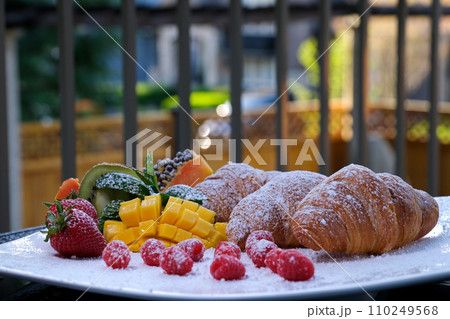 Morning breakfast with croissant and orange juice in glass, yellow roses on vintage silver tray. Morning breakfast with croissant and orange juice in glass, yellow roses on vintage silver tray. 110249568