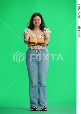 A woman, on a green background, in full height, with a gift 110251984