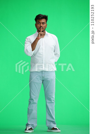 A man in a white shirt, on a green background, in full height, shows a sign of silence A man in a white shirt, on a green background, in full height, shows a sign of silence 110252193