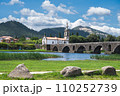 Bridge across the river in Ponte de Lima, southern bank, medieval bridge dates back to 1368, view of the church, river back, mountains or hills on the background, selective focus 110252739