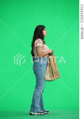 A woman, on a green background, full-length, with bags, in profile 110252911