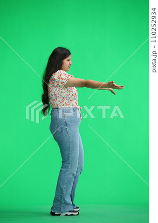 A woman, on a green background, in full height, opens his arms, in profile A woman, on a green background, in full height, opens his arms, in profile 110252934